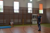sala gimnastyczna, widać stojącego policjant oraz osobę wykonującą ćwiczenie na materacu