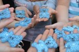 ręce dzieci na których leżą niebieskie misie odblaskowe