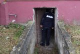 policjant zagląda do piwnicy budynku