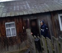 policjant stoi przy starym drewnianym budynku, w drzwiach stoi mężczyzna - odwiedziny w ramach działań &quot;Nie bądźmy obojętni&quot;