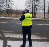 droga, policjant trzyma w ręku urządzenie do pomiaru prędkości
