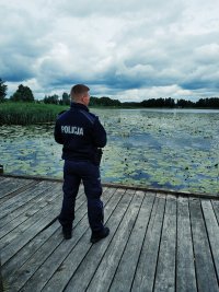 policjant służby patrolowej obserwuje jezioro