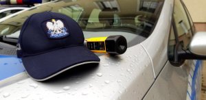policyjna czapka z daszkiem i alkomat leżą na masce radiowozu