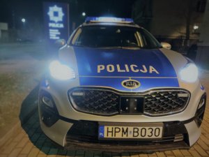 radiowóz Komendy Powiatowej Policji w Sejnach na tle baneru jednostki