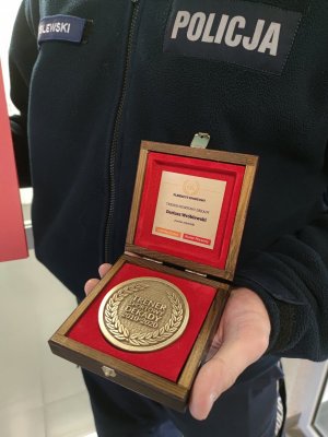 aspirant sztabowy Dariusz Wróblewski trzymający pamiątkowy medal