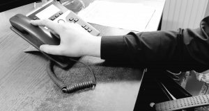 ręka sięgająca za słuchawkę telefonu - zdjęcie czarno-białe