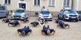 policjanci na tle radiowozów wykonują pompkę