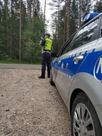 policjant ruchu drogowego przy użyciu miernika prędkości dokonuje pomiaru