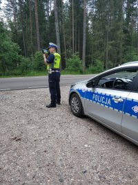 policjant ruchu drogowego przy użyciu miernika prędkości dokonuje pomiaru