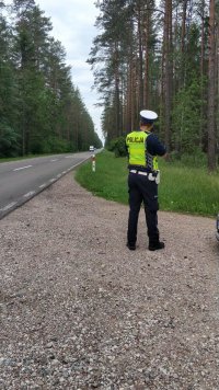 policjant ruchu drogowego przy użyciu miernika prędkości dokonuje pomiaru