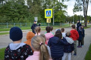 dzieci w towarzystwie policjantki przy przejściu dla pieszych