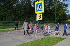 dzieci w towarzystwie policjantki przechodzą przez przejście dla pieszych