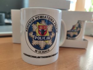 biały kubek z logo Komendy Powiatowej Policji w Sejnach