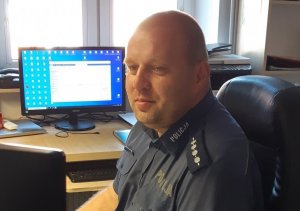 policjant w mudurze przy monitorze komputera wewnątrz budynku