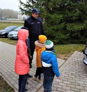 umundurowany policjant rozmawiający z dziećmi