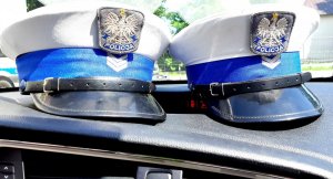 dwie czapki policyjne na kokpicie radiowozu