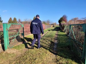 policjant na tle ogródków działkowych