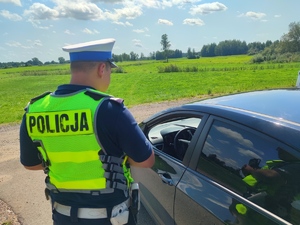 policjant w mundurze stojący przy aucie