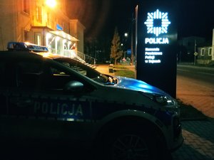 radiowóz na tle baneru Komendy Powiatowej Policji w Sejnach