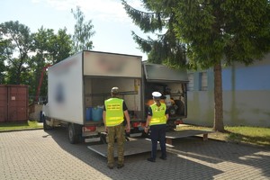 policjantka i strażnik graniczny stoją przy pojazdach dostawczych